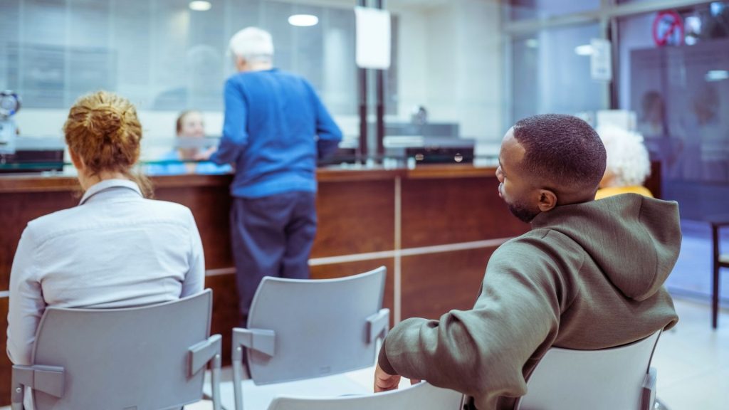 People waiting in a clinic lobby, representing daily check-ins required at Idaho methadone treatment programs.