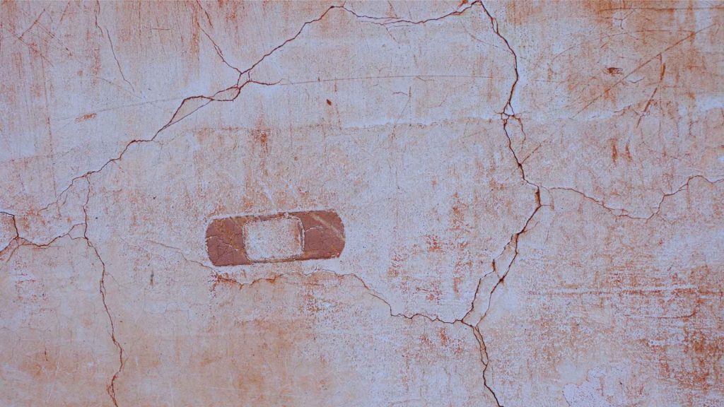 bandage on cracked wall representing physical signs of heroin addiction.