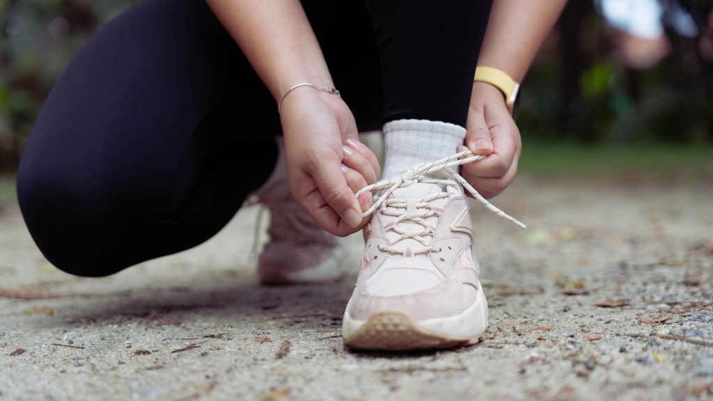 Tying running shoes as part of building healthy habits to help reduce opioid cravings during recovery.