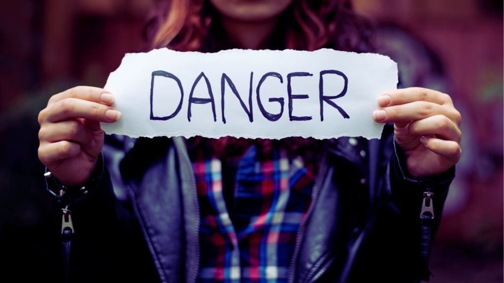 Hands holding a sign that reads “Danger,” representing the risks of fentanyl addiction.